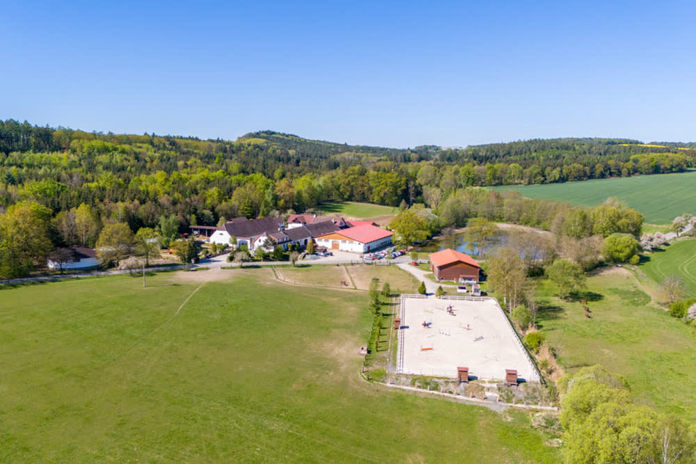 Farma s jízdárnou a lesy okolo
